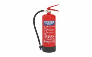 The Firechief XTR 6kg Powder Fire Extinguisher (FXP6) is shown standing upright on a white background, featuring a red body with a "Powder" label and instructions on the front, a black hose attached to the side, and a red handle on top. | Work & Wear DIrect