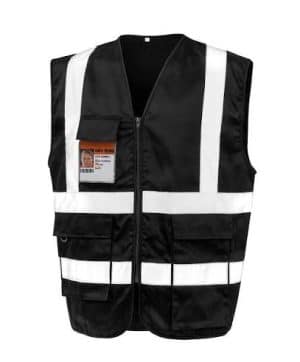 A black, zippered safety vest with horizontal and vertical white reflective stripes. It features two large lower pockets and a smaller upper chest pocket holding a clear plastic badge holder containing an identity card. Isolated on a white background. | Work & Wear DIrect