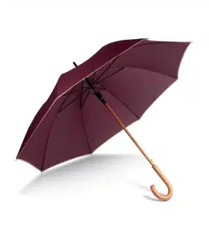 A maroon umbrella with a wooden curved handle is open and lying on its side against a white background. | Work & Wear DIrect