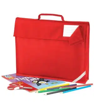 A red rucksack with a handle and name tag, shown with scissors, coloured pencils, a ruler, and a timetable book arranged in front of it. | Work & Wear DIrect